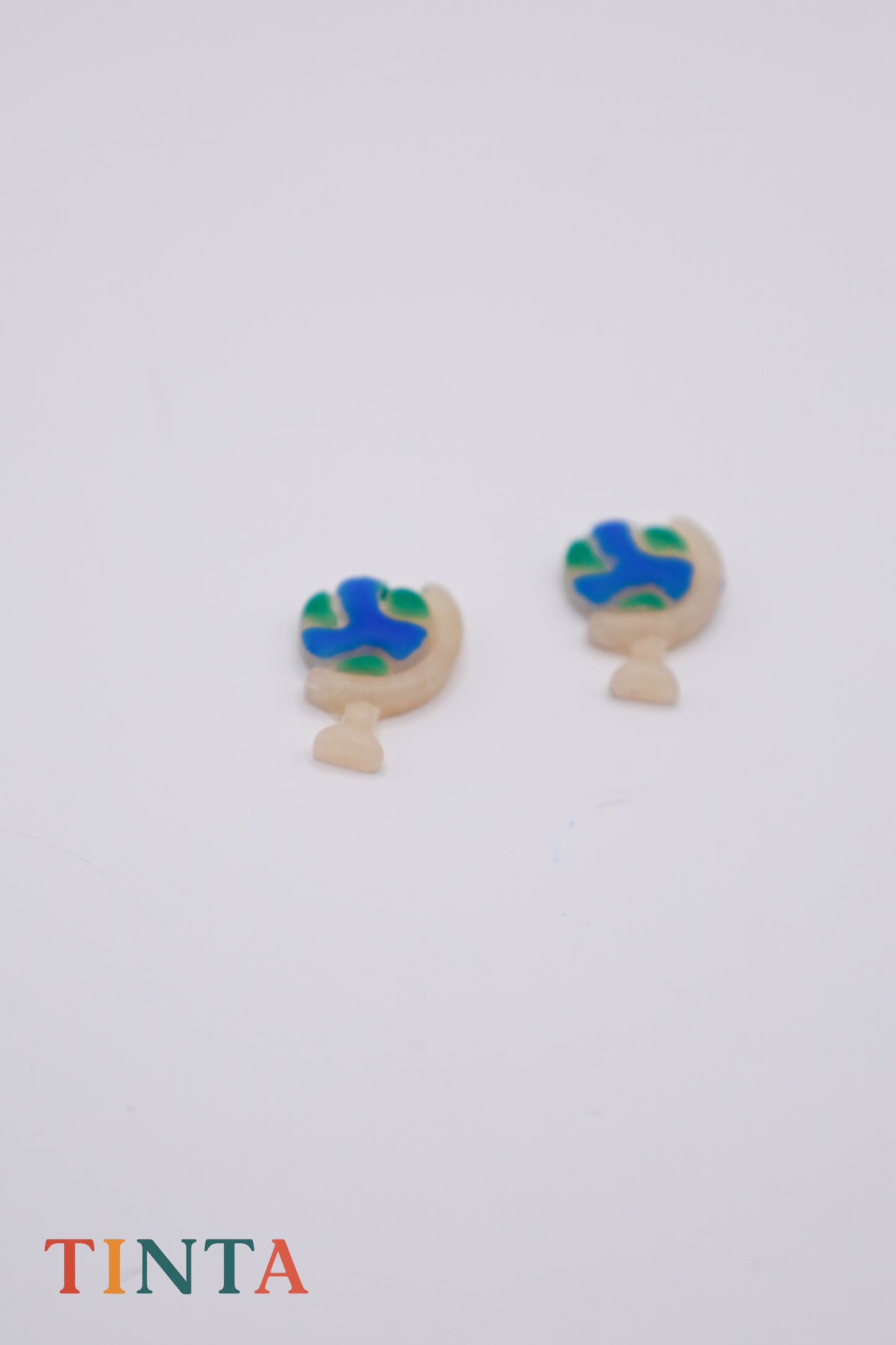 Pair of earrings with blue and green design on a white background, featuring the brand 'TINTA'.