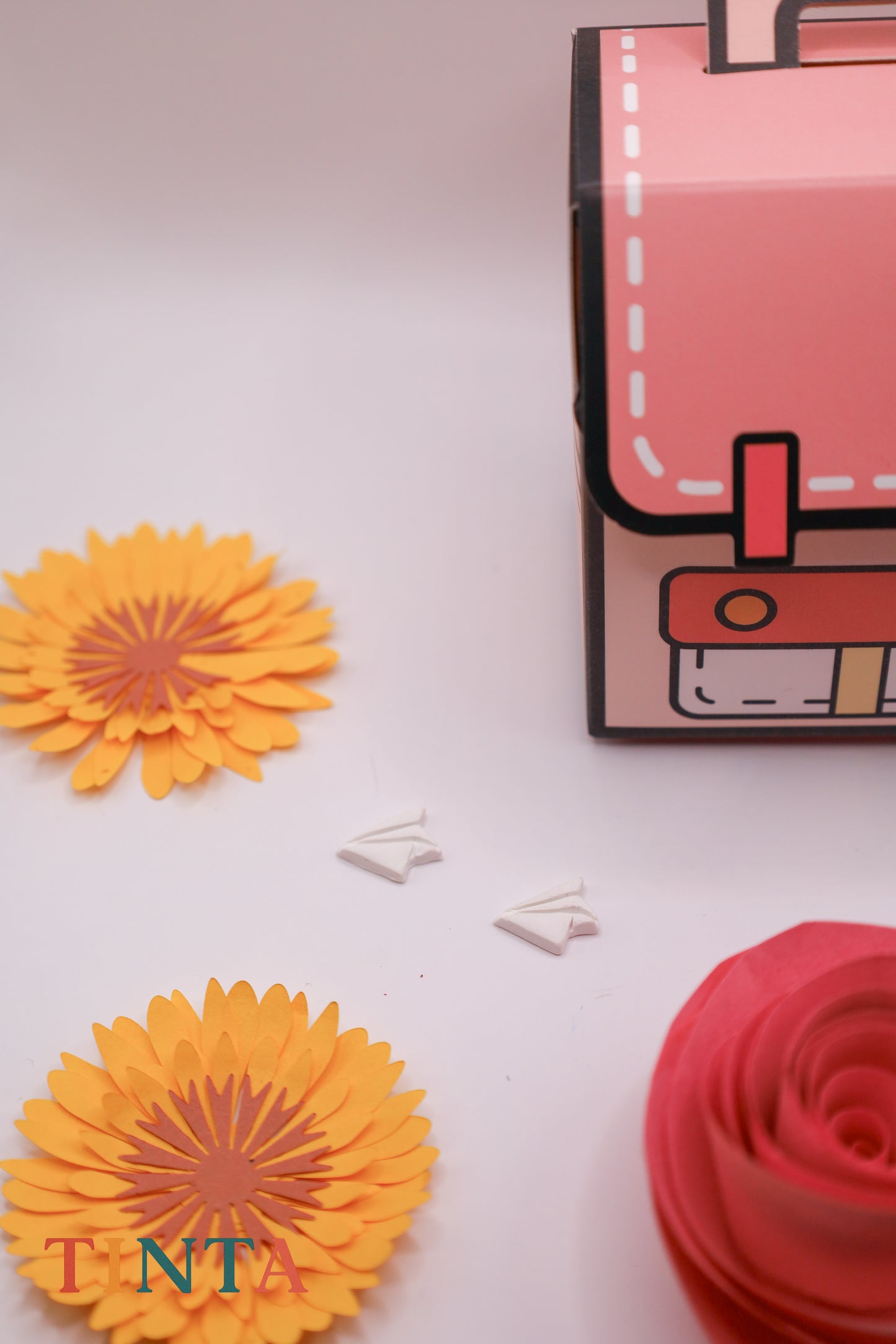 Colorful paper flowers and a small book on a white background