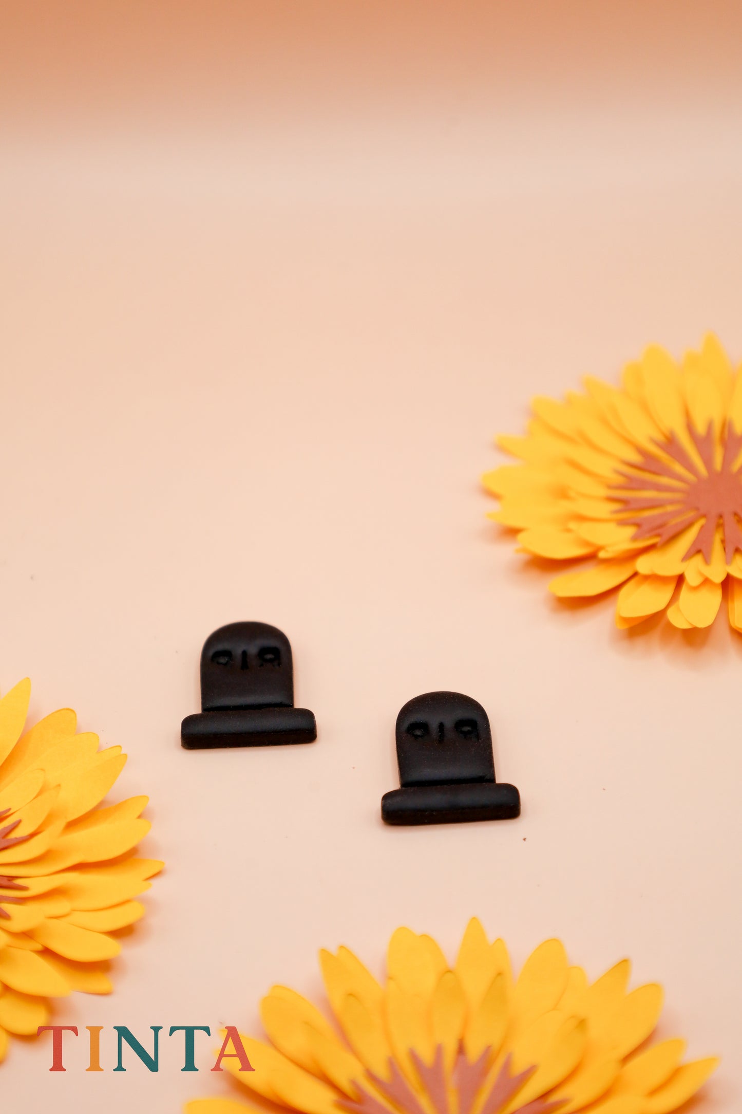 Black hair clips on a beige background with yellow flowers, featuring the brand 'Tinta'.