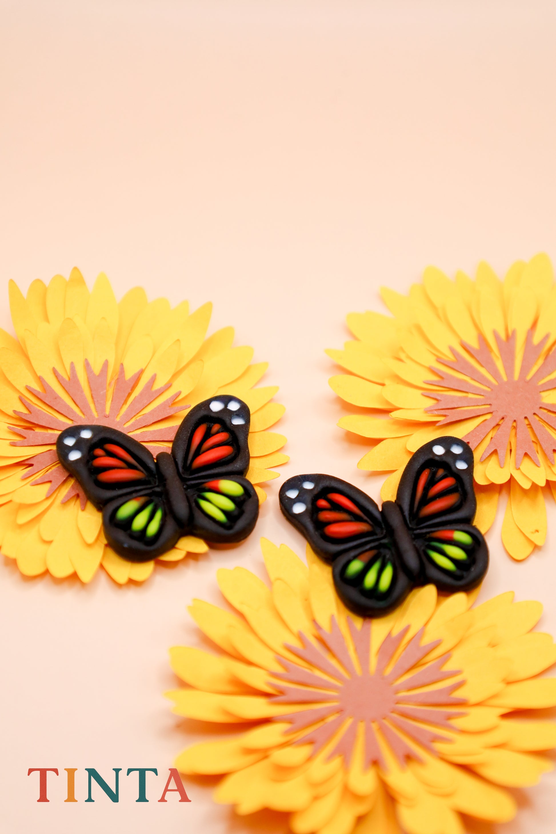 Butterfly and flower decorations on a beige background with 'TINTA' branding.