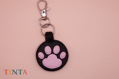 Keychain with pink paw print design on a beige background, featuring the brand 'TINTA'.