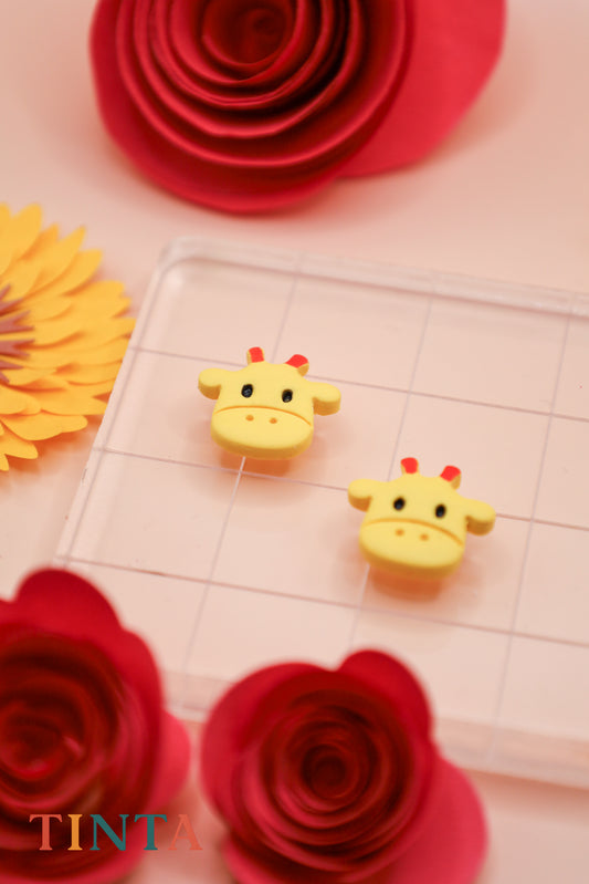 Yellow giraffe-shaped erasers on a grid background with red and orange paper flowers.