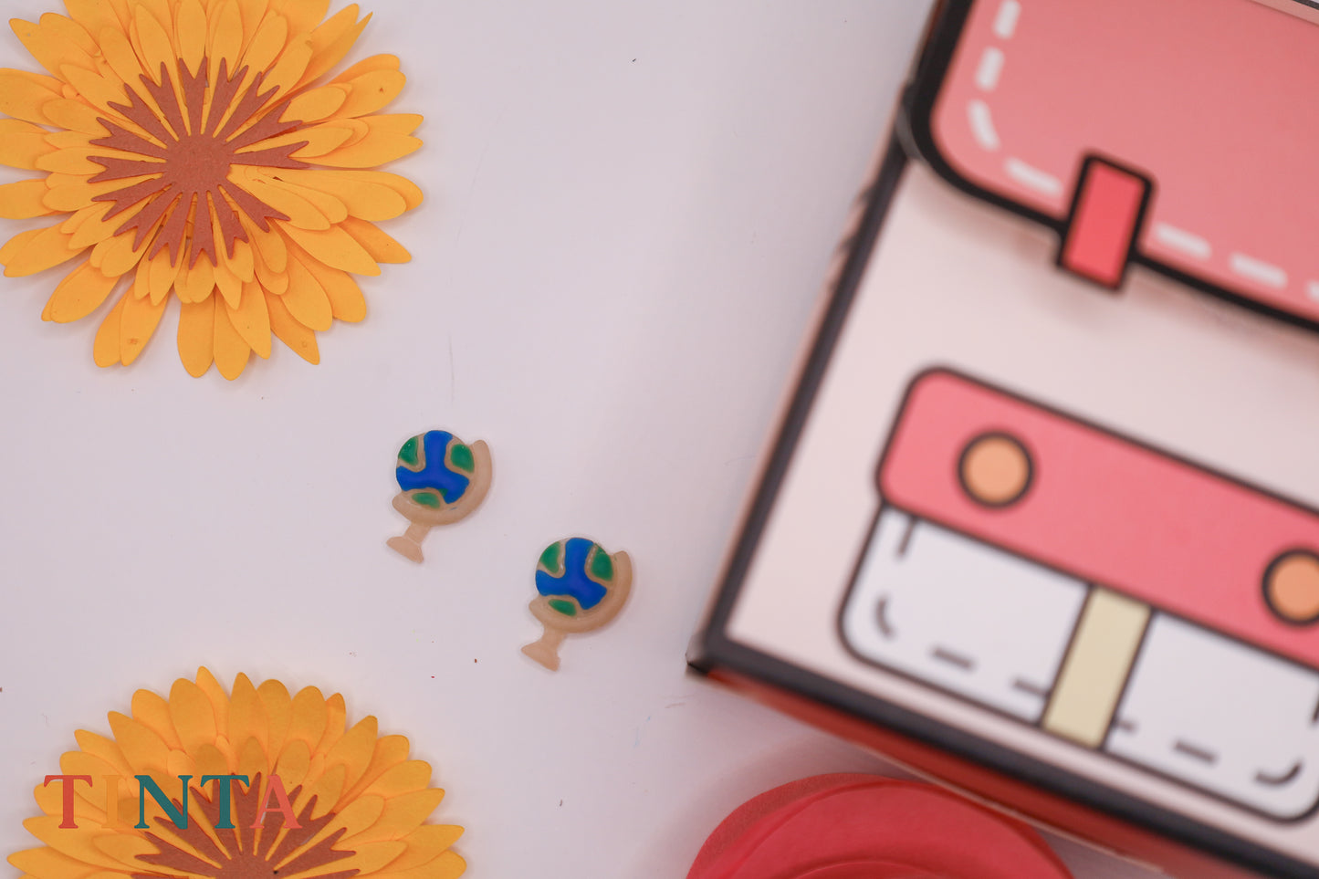 Decorative items including a pink cassette tape, orange flowers, and small green and blue figurines on a white background.