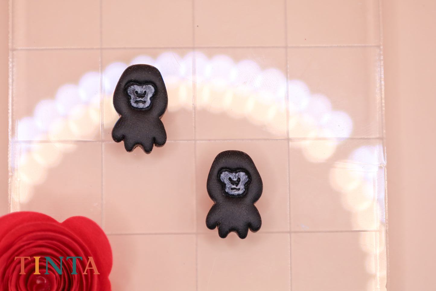 Black gorilla-shaped bath mats on a tiled bathroom floor with a red flower and 'TINTA' branding.