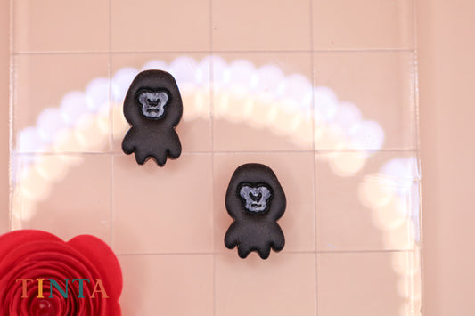 Black gorilla-shaped bath mats on a tiled bathroom floor with a red flower and 'TINTA' branding.