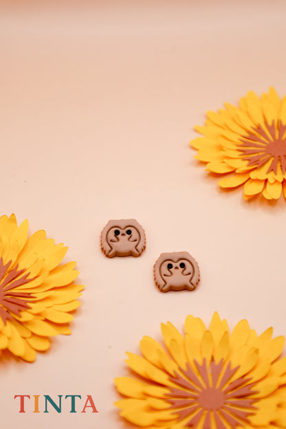 Two small animal-shaped cookies with a beige background and yellow flowers, featuring the brand 'Tinta'.