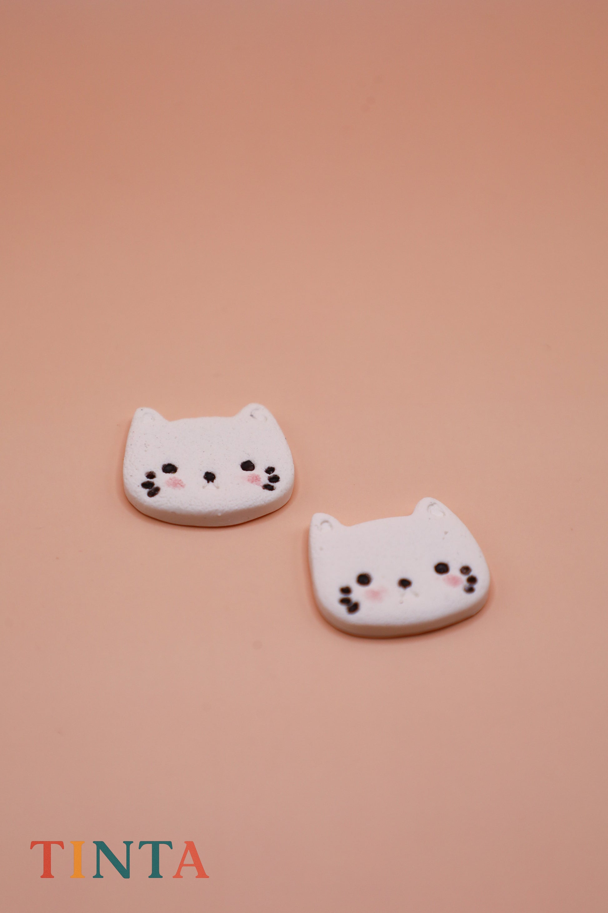 Two cat-shaped cookies on a pink background with 'TINTA' branding.