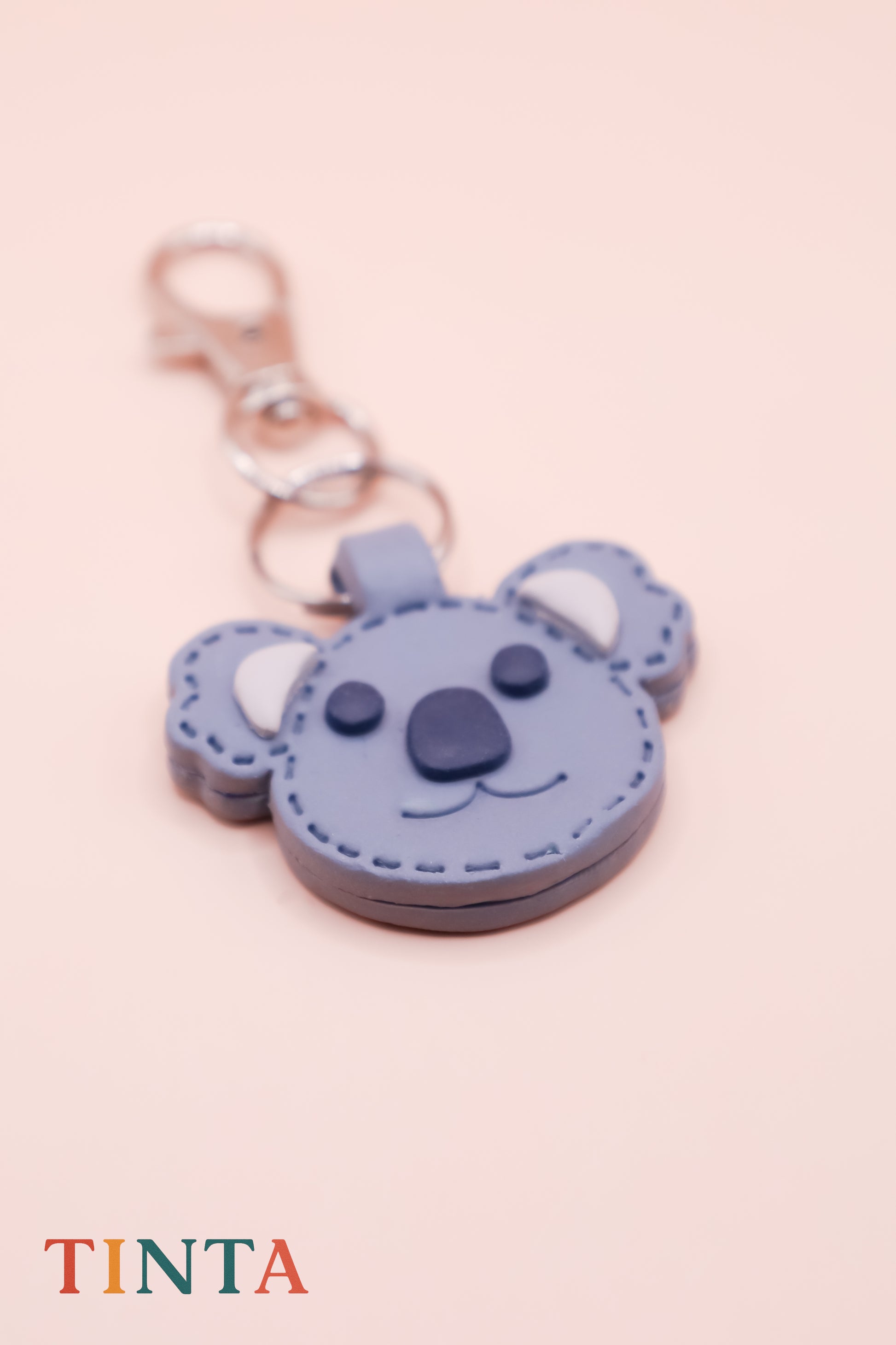 Blue koala-shaped keychain with a pink background
