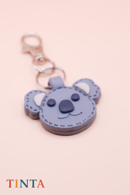 Blue koala-shaped keychain with a pink background