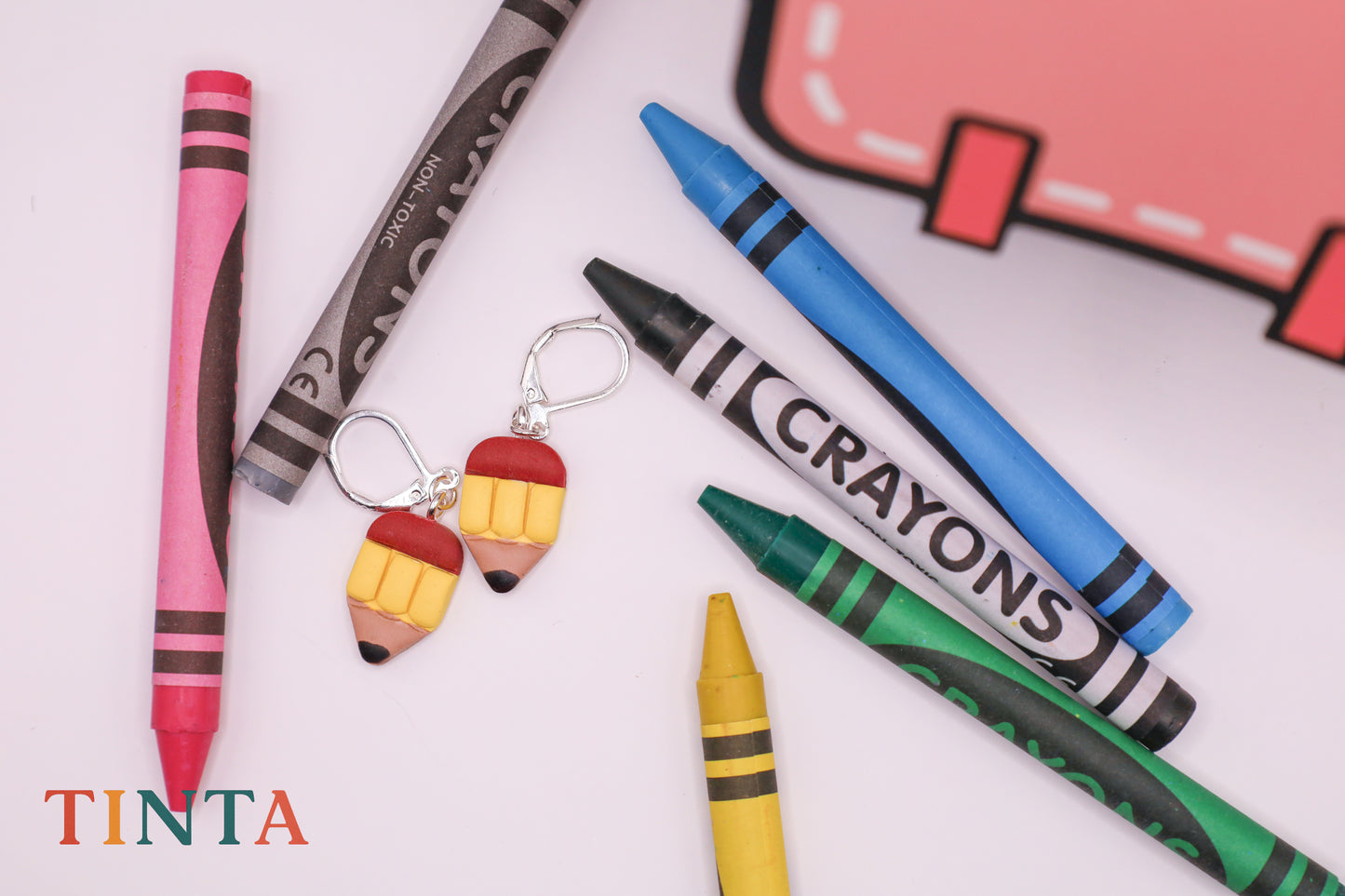 Crayon-shaped earrings with crayon-themed background