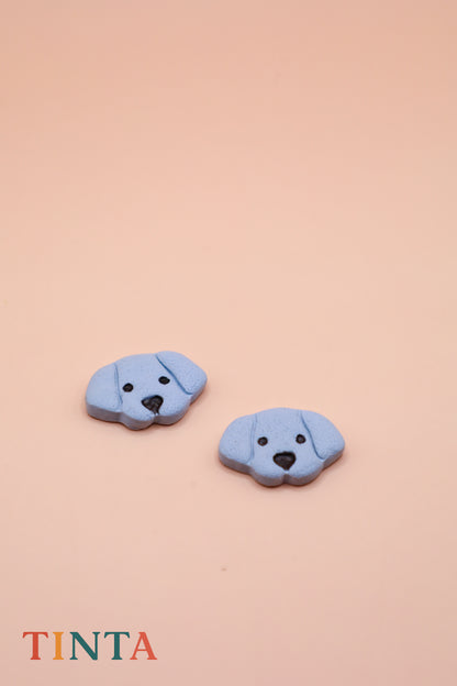 Two blue dog-shaped buttons on a beige background with 'TINTA' branding.