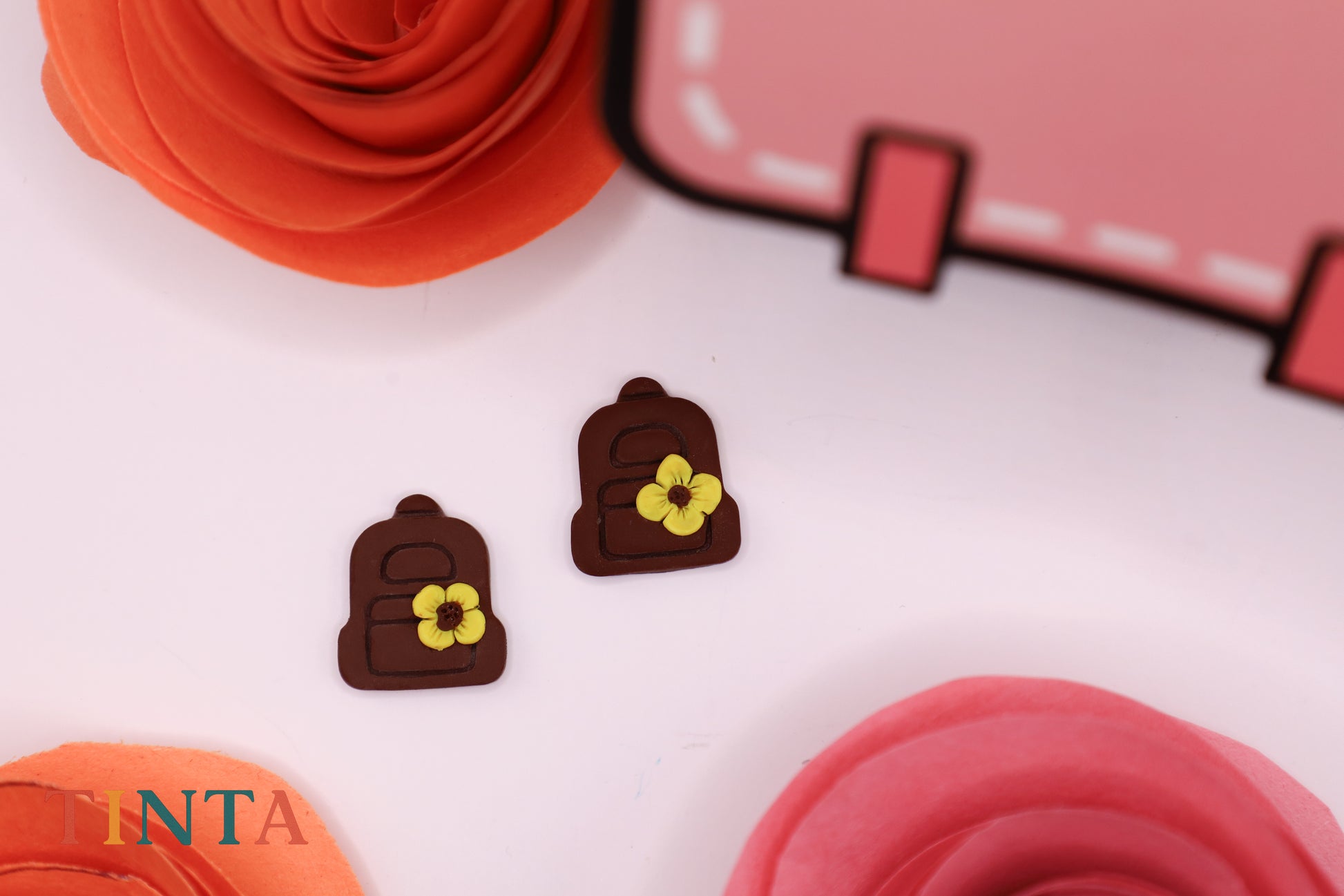 Chocolate-shaped earring with floral designs on a white surface