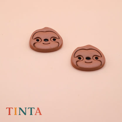 Two brown clay face stamps on a beige background with 'TINTA' branding.