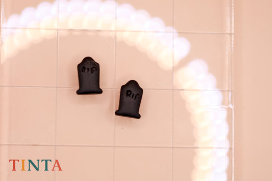 Two black tombstone-shaped objects with 'RIP' on a tiled wall, featuring the brand 'TINTA'.