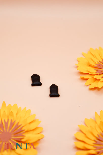 Black earrings on a beige background with yellow flowers and 'TANTA' branding.