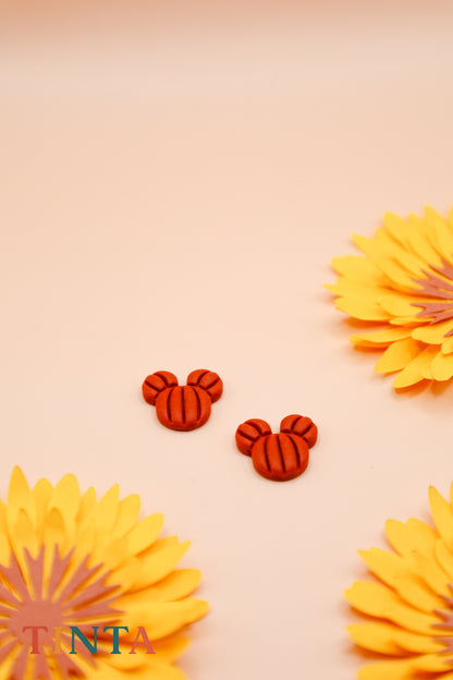 Red mouse ear-shaped earrings on a beige background with yellow flowers.