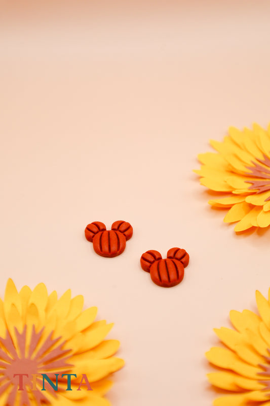 Red mouse ear-shaped earrings on a beige background with yellow flowers.